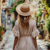 Woman wearing a linen midi dress and straw hat walking through a European street - a chic example of Europe summer outfits.
